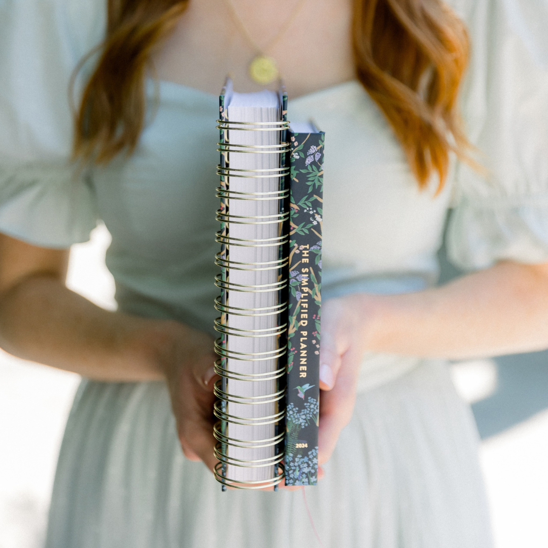 young woman holding a daily and weekly Simplified Planner up for comparison
